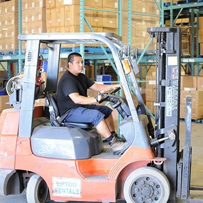 Warehouse employee working with forklift in warehouse.